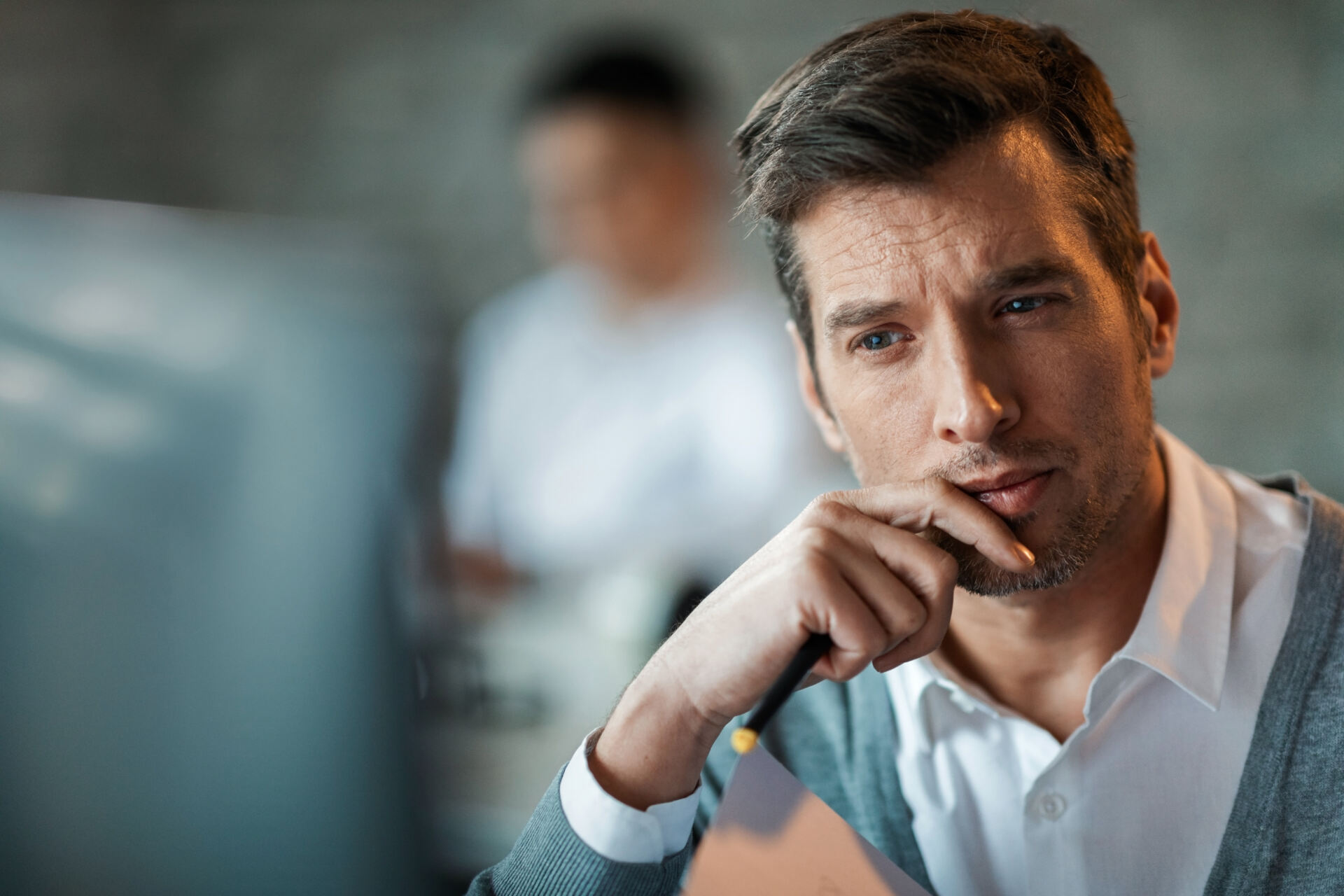 Pensive businessman reading something on the computer in the office.